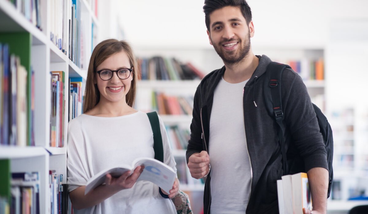 happy students couple in school library have discussion about book